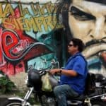 A motorcyclist passes by a giant grafitt