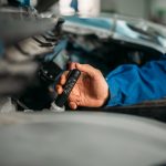 Male technician checks brake fluid level in car