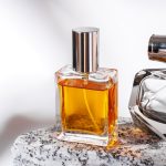 Perfume bottle on granite stones against white background with shadows